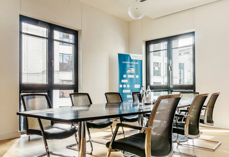 Besprechungsraum im Hamburger Büro mit langem Tisch, Stühlen und großen Fenstern